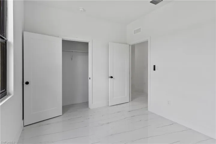 Unfurnished bedroom featuring light marble finish floors and a closet