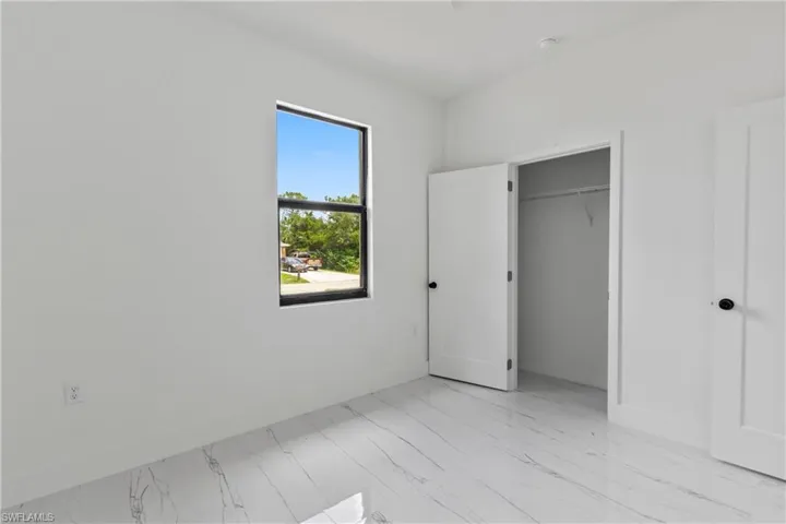 Unfurnished bedroom featuring light marble finish flooring and baseboards