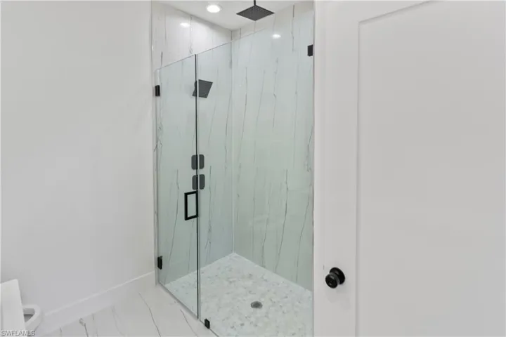 Bathroom featuring a marble finish shower and marble look tile flooring