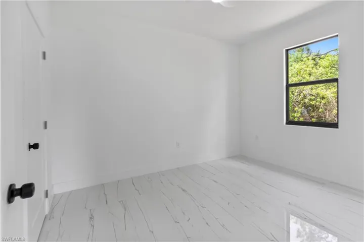 Unfurnished room with marble look tile flooring and baseboards