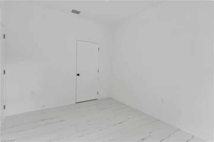 Spare room with light marble finish flooring and baseboards