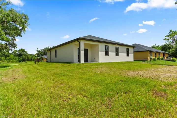 Rear view of house with stucco siding and a yard