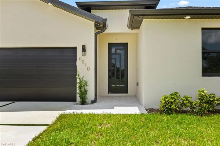 Doorway to property featuring stucco siding, an attached garage, and concrete driveway