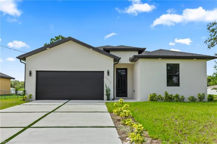 View of front facade featuring an attached garage, stucco siding, and driveway