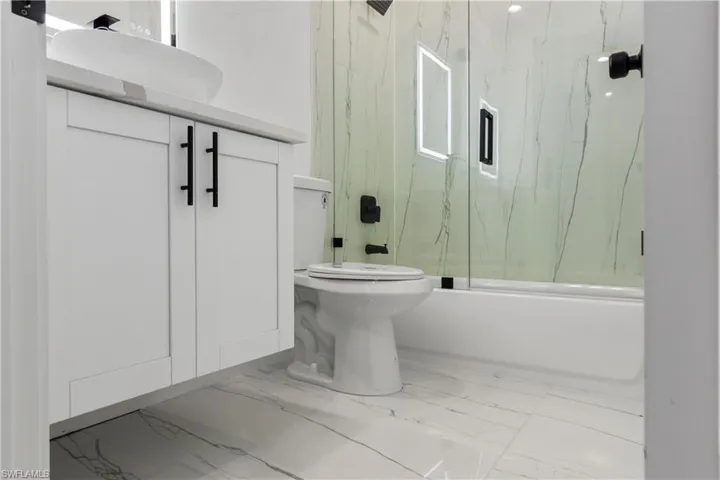 Full bath with marble look tiles and vanity