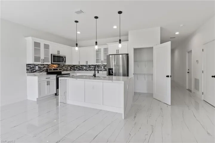 Kitchen with appliances with stainless steel finishes, decorative backsplash, light countertops, white cabinets, and recessed lighting