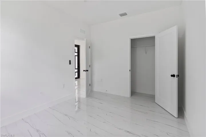Unfurnished bedroom featuring light marble finish flooring and a closet