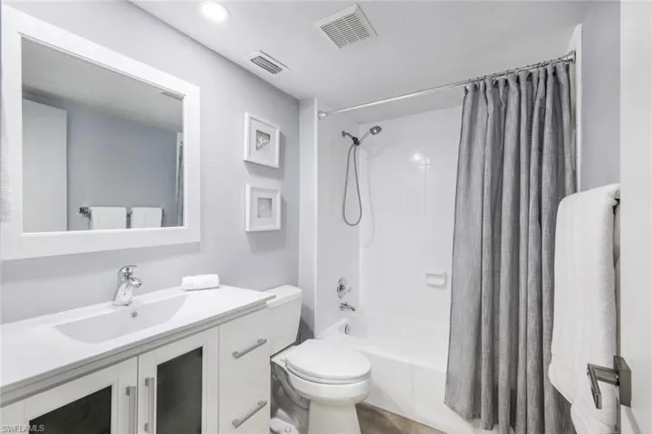 Full bathroom with shower / bath combo with shower curtain, toilet, and large vanity