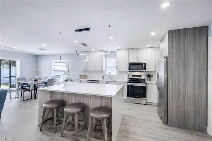 Kitchen featuring decorative light fixtures, light hardwood / wood-style flooring, a healthy amount of sunlight, appliances with stainless steel finishes, and sink