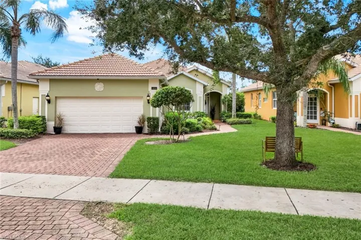 View of front of property featuring stucco siding, a front yard, a tiled roof, decorative driveway, and a garage