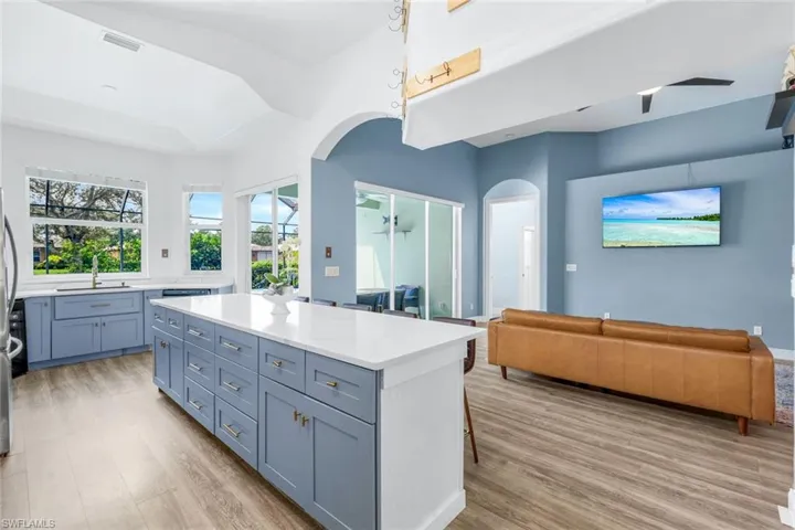 Kitchen featuring open floor plan, a breakfast bar, light wood-style flooring, light stone countertops, and a center island
