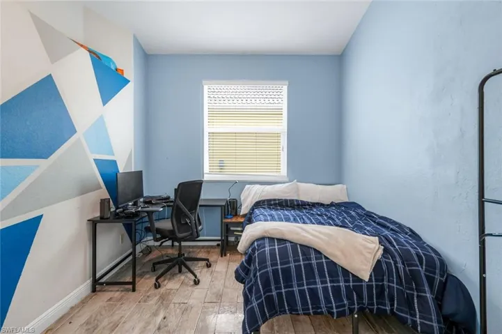 Bedroom with wood finished floors and a desk