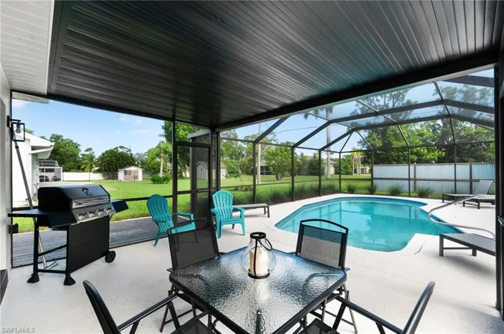 Outdoor pool with a patio, grilling area, a sunroom, glass enclosure, and outdoor dining area