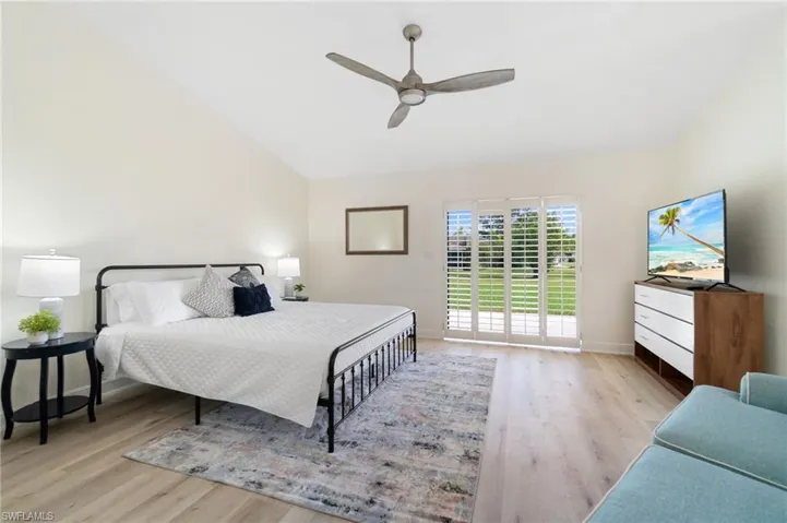Bedroom with light wood-style flooring, access to exterior, ceiling fan, and vaulted ceiling