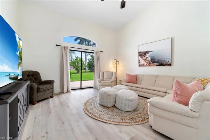 Second living area featuring light wood-style flooring, lofted ceiling, and a ceiling fan