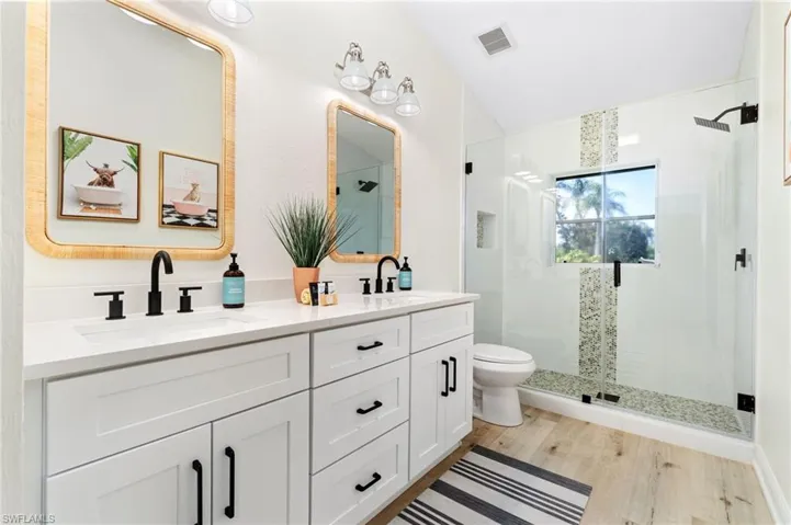 Bathroom featuring double vanity, a shower stall, and light wood finished floors