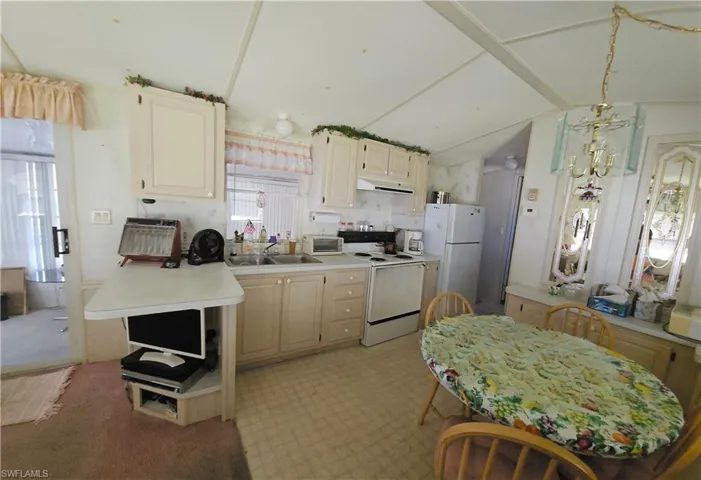Kitchen featuring lofted ceiling, sink, and white appliances
