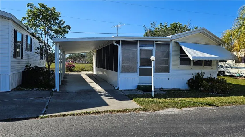 View of front of house featuring a carport, a sunroom, and a front yard