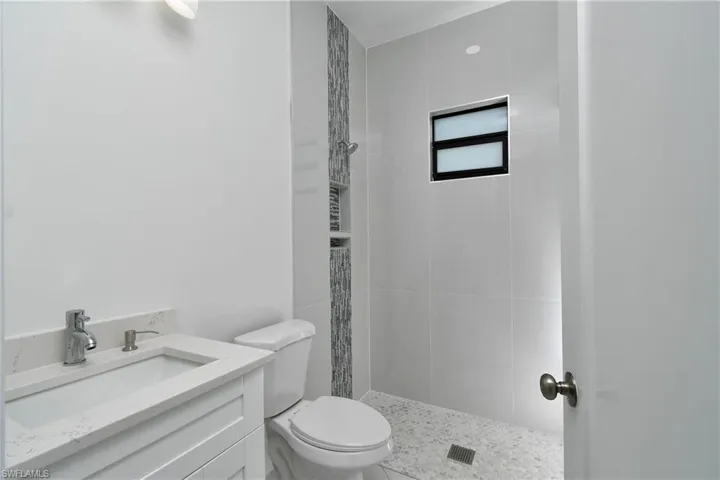 Bathroom featuring toilet, vanity, and a tile shower