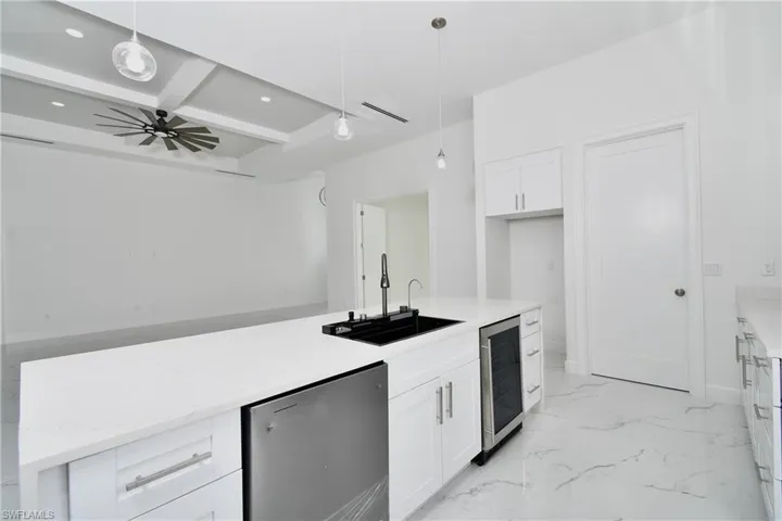 Kitchen featuring hanging light fixtures, white cabinets, beverage cooler, and stainless steel refrigerator