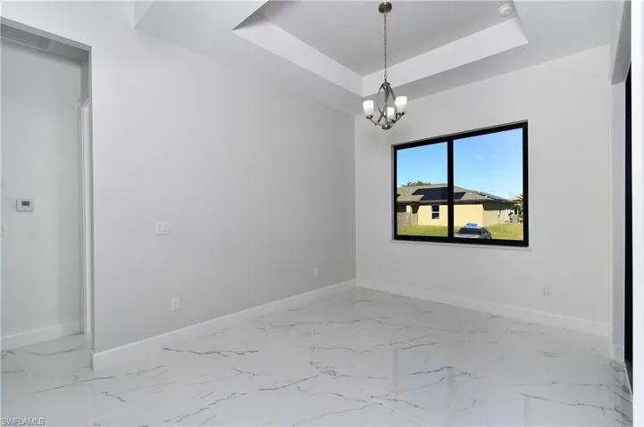 Unfurnished room featuring a raised ceiling and a chandelier