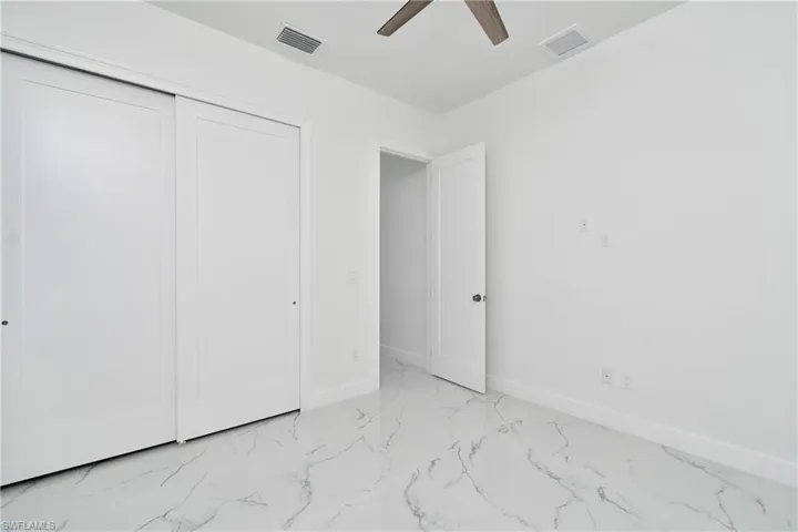 Unfurnished bedroom with ceiling fan and a closet