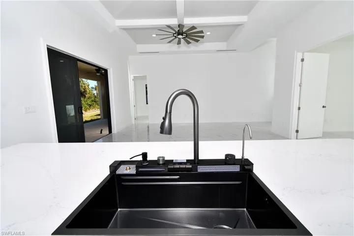 Kitchen featuring beamed ceiling, light stone counters, and sink