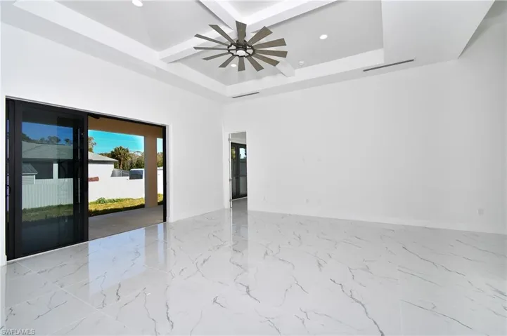 Unfurnished room featuring a raised ceiling, ceiling fan, and coffered ceiling