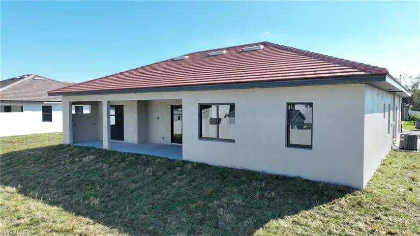 Rear view of property featuring a patio area, a lawn, and central AC