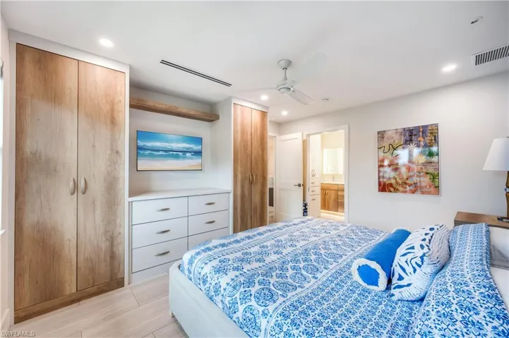 Bedroom with multiple closets, a ceiling fan, ensuite bath, and recessed lighting