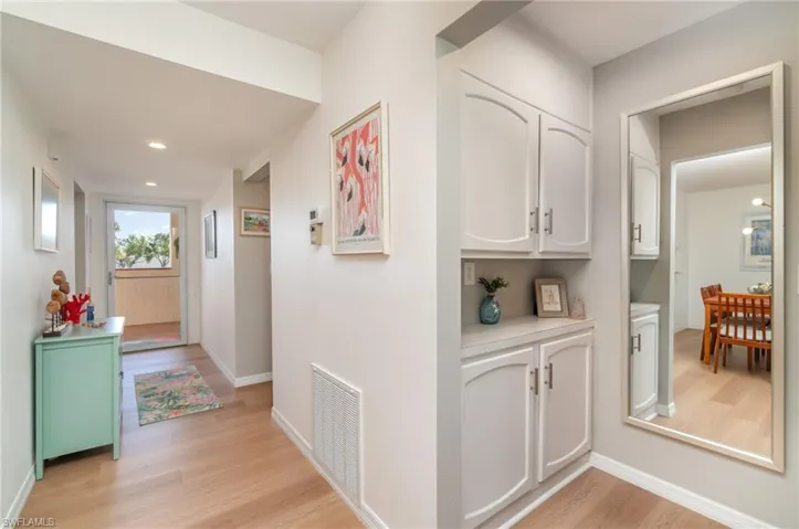 Hallway towards front door and primary bedroom with storage and recessed lighting