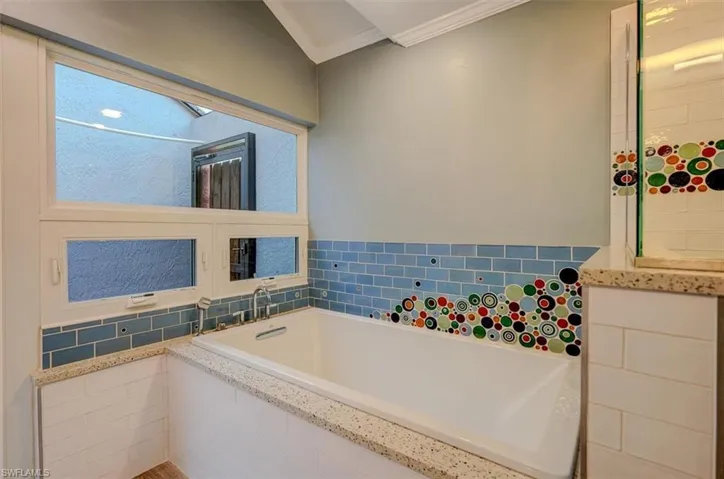 Bathroom with ornamental molding and tiled tub