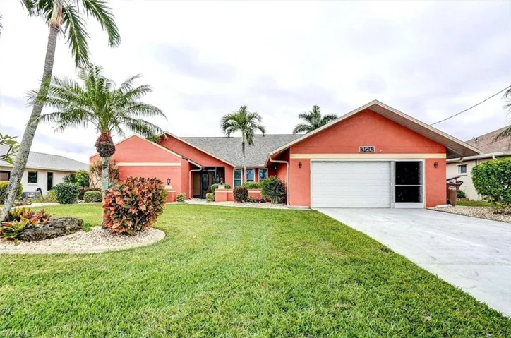 Single story home with a garage and a front lawn