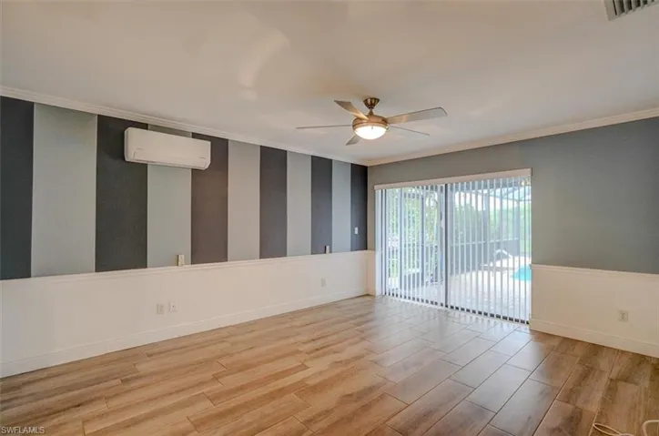 Empty room featuring light hardwood / wood-style flooring, an AC wall unit, ceiling fan, and ornamental molding