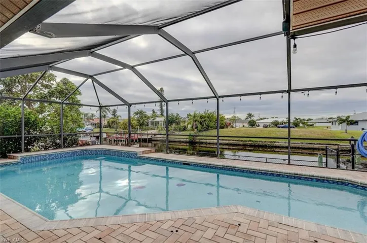 View of swimming pool with glass enclosure and a patio area