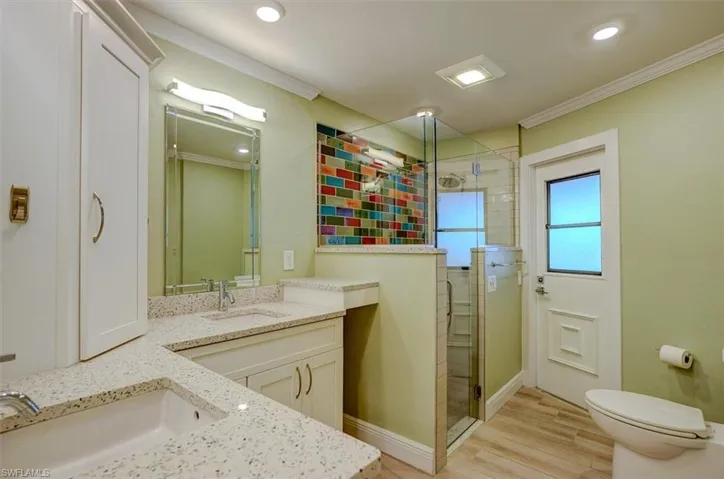 Bathroom with crown molding, vanity, hardwood / wood-style flooring, and walk in shower