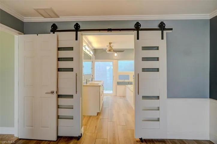Hall with a barn door, light hardwood / wood-style floors, sink, and ornamental molding