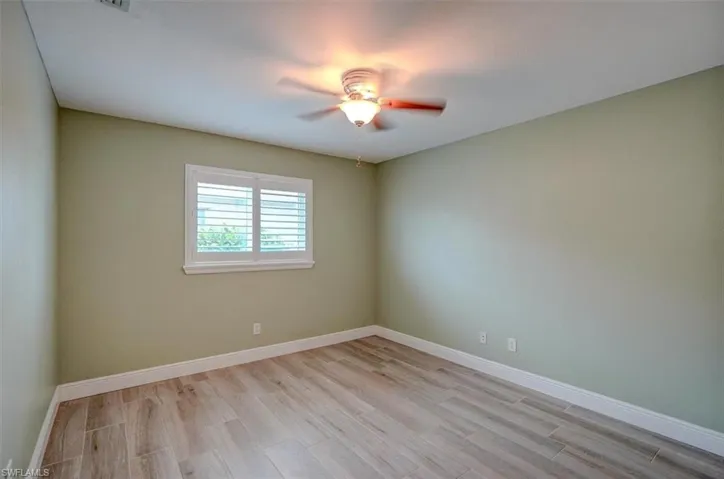 Empty room with ceiling fan and light hardwood / wood-style floors
