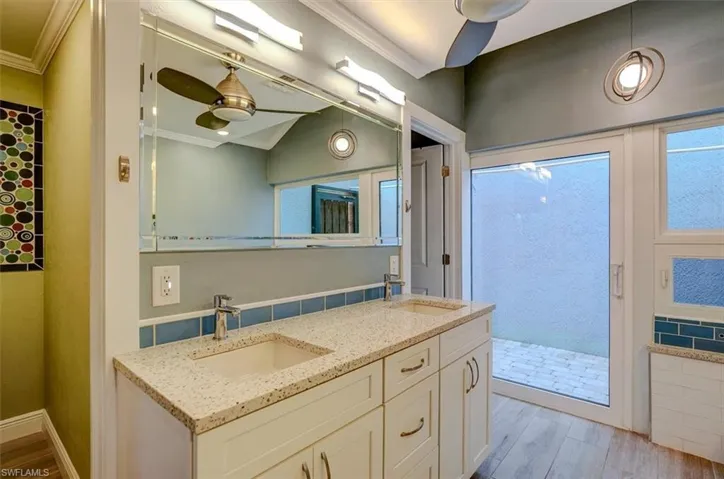 Bathroom featuring ceiling fan, crown molding, vanity, and walk in shower