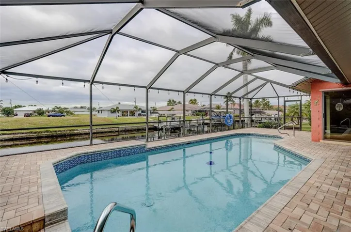 View of pool featuring a lanai, a patio, and a water view