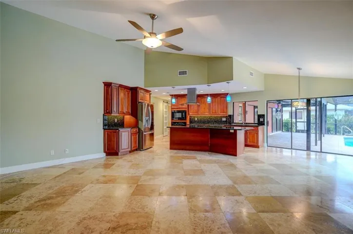 Kitchen featuring island exhaust hood, stainless steel refrigerator with ice dispenser, backsplash, black microwave, and ceiling fan