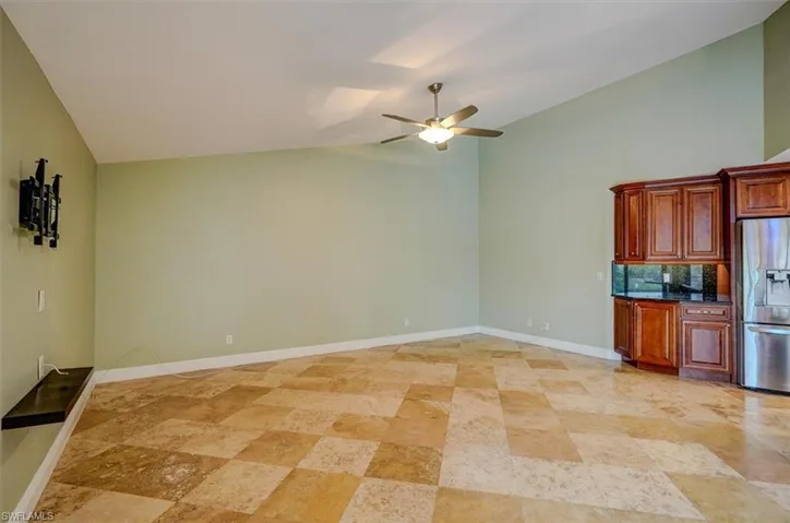 Kitchen with vaulted ceiling, decorative backsplash, ceiling fan, and stainless steel refrigerator with ice dispenser