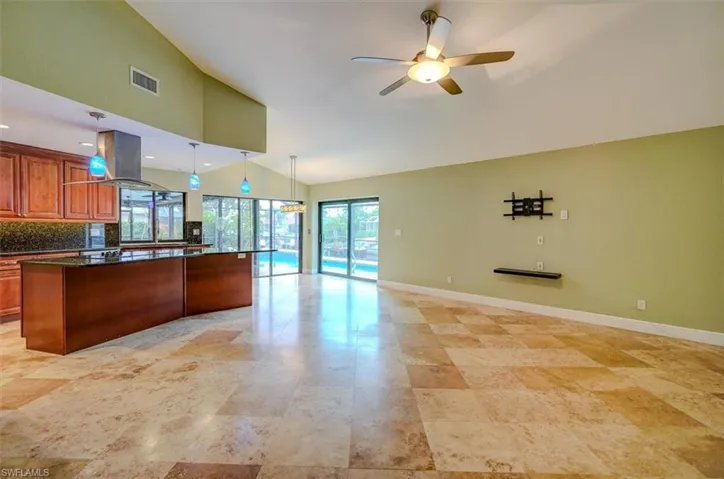 Kitchen featuring high vaulted ceiling, ceiling fan, decorative backsplash, decorative light fixtures, and island exhaust hood