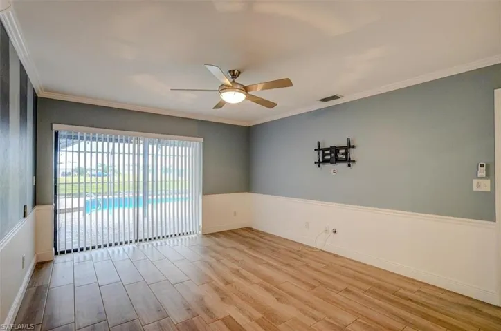 Spare room with light wood-type flooring, ceiling fan, and ornamental molding