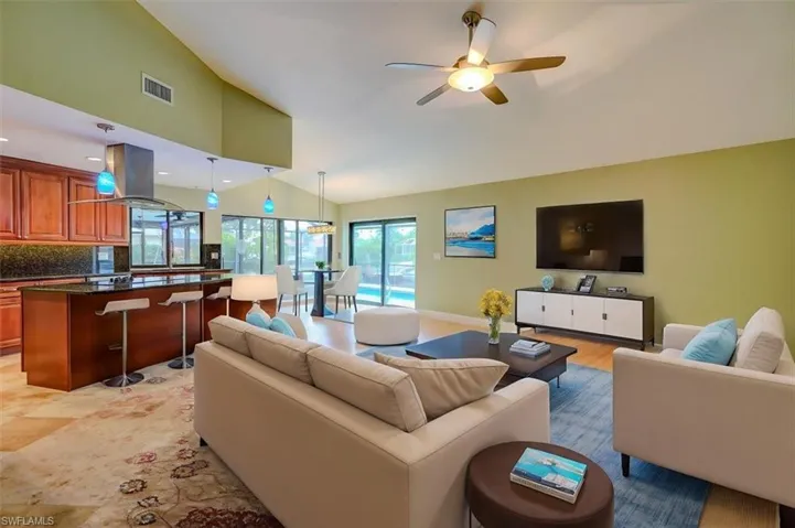 Living room with high vaulted ceiling, light hardwood / wood-style flooring, and ceiling fan