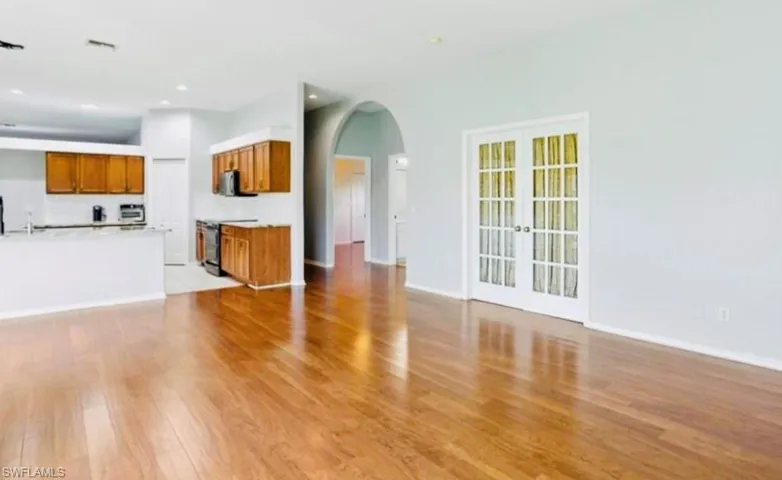 Unfurnished living room featuring arched walkways, light wood-type flooring, french doors, and recessed lighting