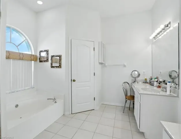 Bathroom with vanity, a bath, and light tile patterned floors