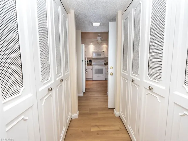 Hall featuring a textured ceiling and light hardwood / wood-style flooring
