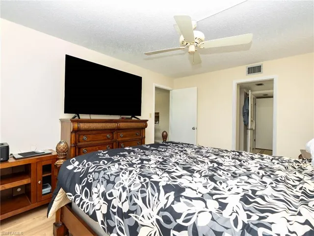 Bedroom featuring ceiling fan, a textured ceiling, and light wood-type flooring