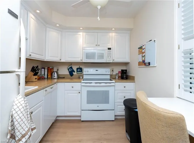 Kitchen featuring light wood-type flooring, white appliances, ceiling fan, and white cabinetry
